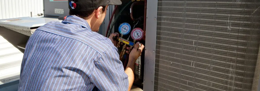 HVAC technician servicing a condenser unit in Wanaque